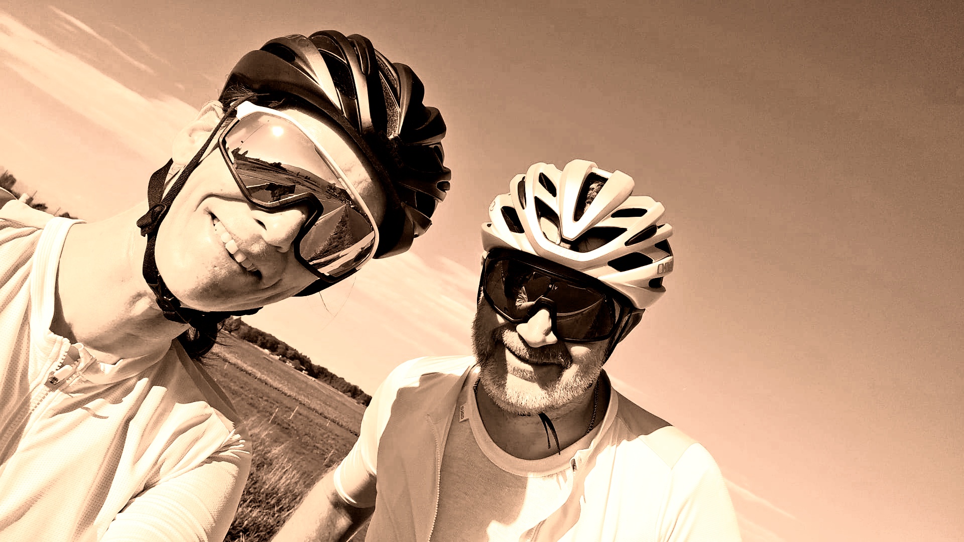 Laure et Franck à vélo, casques et lunettes, sourire au soleil